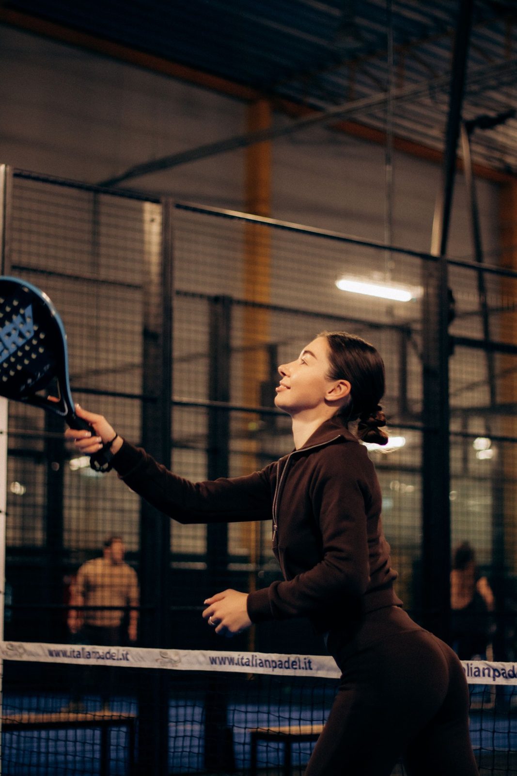 Padel player playing a shot near the glass wall of an indoor court